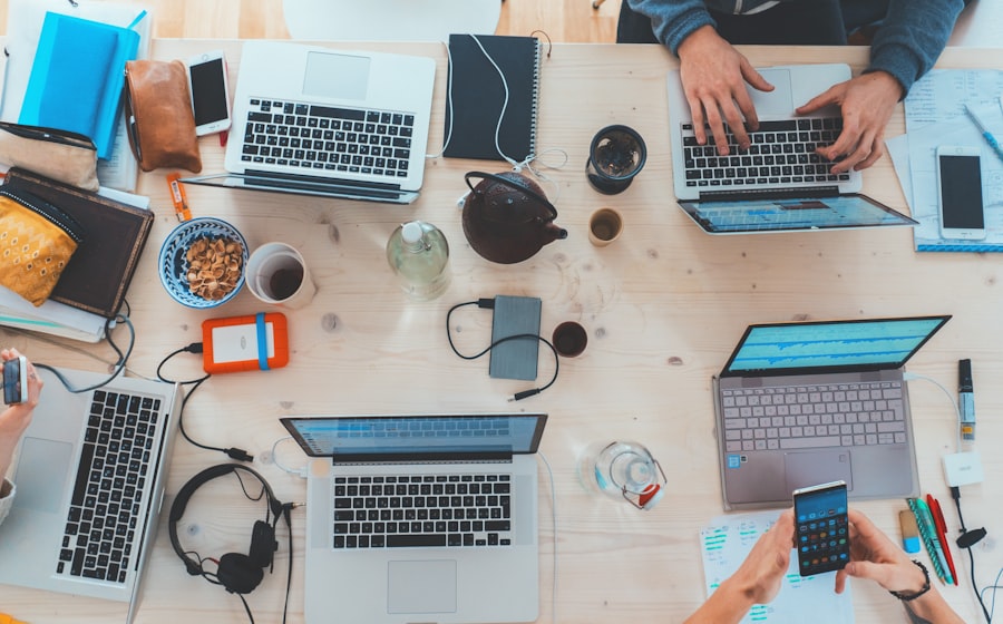 Widok z góry na biurko z kilkoma laptopami i urządzeniami podczas pracy